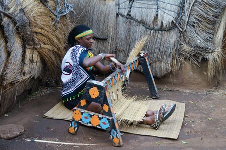 Lesedi Cultural Village, South Africa - 20 October 2016: Unidentified African Zulu woman wearing traditional handmade costume, weave straw carpet in Lesedi African Cultural village, South Africaのeditorial素材