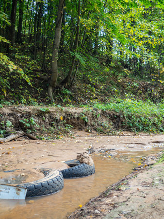 Tires in the sand at the bottom of the stream. Bad ecologyの写真素材