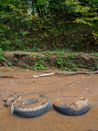 Tires in the sand at the bottom of the stream. Bad ecologyの写真素材