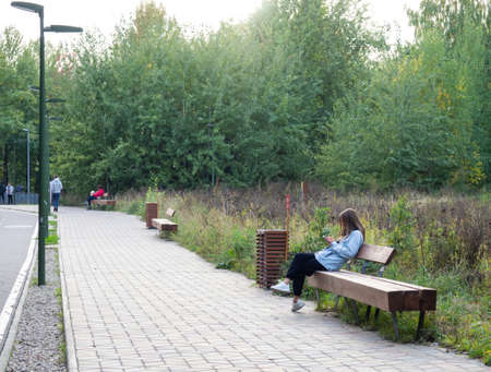 A girl sitting on a park benchの写真素材