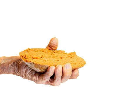 Elderly woman's hand holds out a piece of rye bread on a white backgroundの写真素材