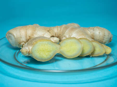 Cut ginger root on a transparent plate. Blue background.の写真素材