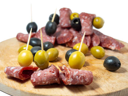 Slicing salami and olives on toothpicks. Slicing on a kitchen boardの写真素材