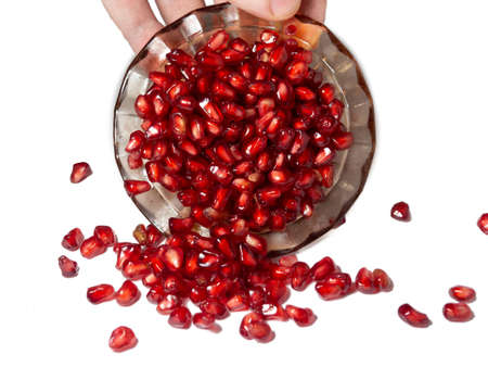 Man's hand sprinkles pomegranate seeds from a saucerの写真素材