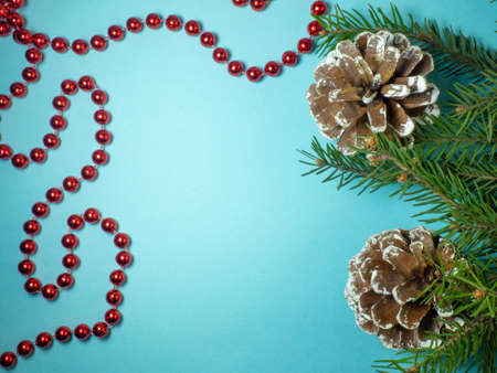 New Year card. Christmas card on blue background.  Fir branches. Decorations for the holiday. Red beads and fir conesの写真素材