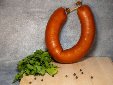 The sausage lies on a kitchen board with black peppercorns and bay leaves.の写真素材
