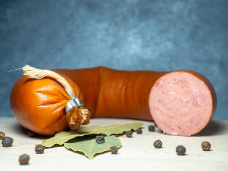 Sliced ââsausage on a cutting board with laurel leaves and black peppercorns.Slicing. Spicesの写真素材