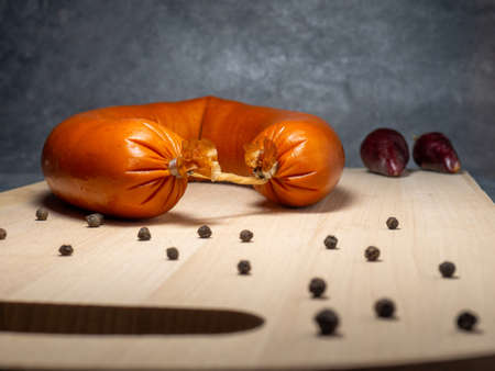 The sausage lies on a kitchen board with pepperの写真素材
