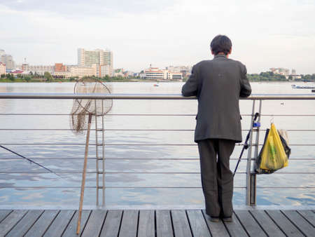 Fisherman on the shore of the city lakeの写真素材