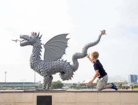 The boy touches the dragon statue. The symbol of the city.の写真素材