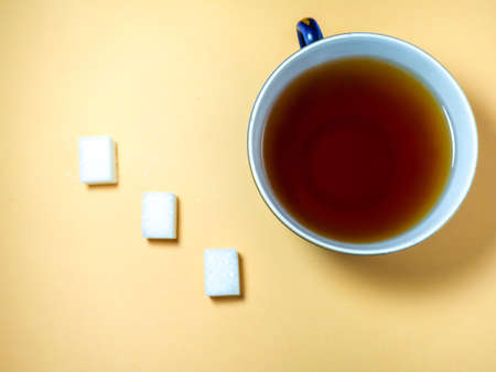 Pieces of sugar a cup of tea on a beige background. Sweet product. Tea drinkingの写真素材