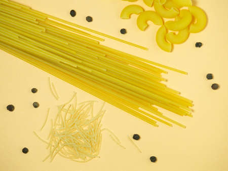 spaghetti, pasta horns and noodles on the table. Black peppercornsの写真素材