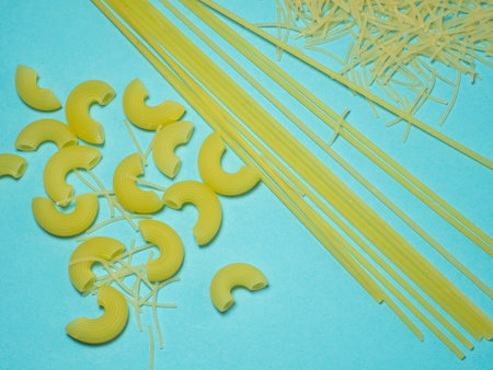 Pasta of different types on a blue background. Raw pastaの写真素材
