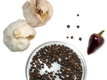 garlic, hot peppers and black peppercorns on a white background.の写真素材
