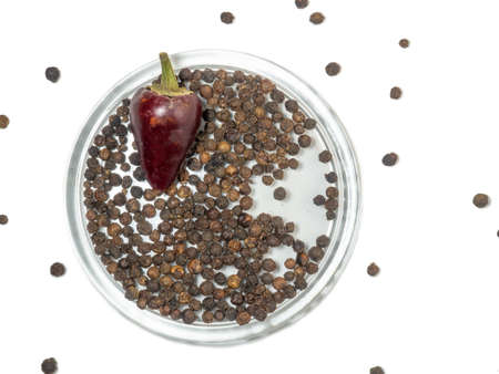hot pepper and black peppercorns in glass plate on a white background.の写真素材