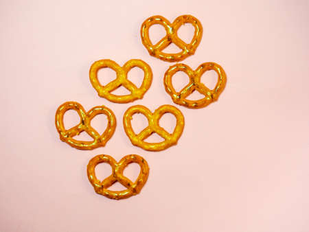 A bunch of pretzels are spread out on the table.Pastries of an interesting unusual shape.Pretzel background.Small salty pretzels on a pink background. Flour product. A delicacy for tea. Wicker crispy biscuits.の写真素材