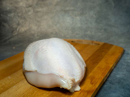 Whole chicken breast with skin on a cutting board. Food on a black background. Raw meat. Cooking chicken.の写真素材