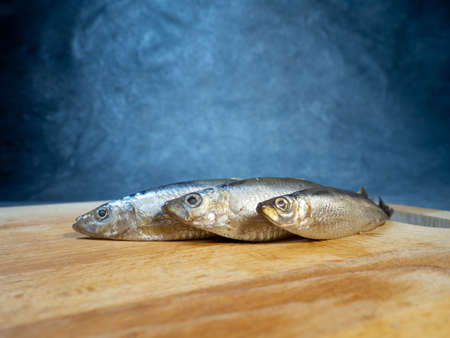 Lightly salted sprat on a cutting board. Whole small fish on the table. Snack. Cookingの写真素材