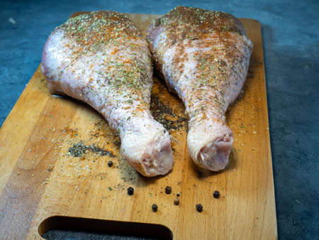 Turkey drumsticks in spices lie on a kitchen cutting board. Poultry meat. Turkey leg. Juicy meat is waiting to be cooked. Waiting for the oven. Hamの写真素材