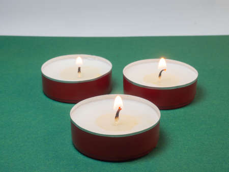 Flat candles on the table. Small candles on a green background.の写真素材