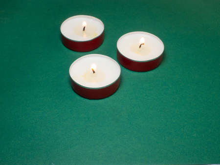 Flat candles on the table. Small candles on a green background.の写真素材