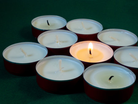 Short candles are burning on a green surface. Lots of small candles. Not all candles are lit. Extinguishedの写真素材