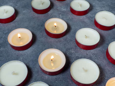 Short candles are burning against a dark background. Lots of small candles. Not all candles are lit. Extinguishedの写真素材