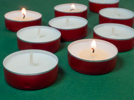 Flat candles on the table. Small candles on a green background. Candles not burning. Not all candles litの写真素材