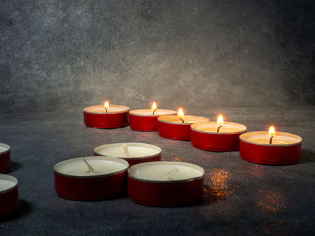 Short candles are burning on a dark surface. Lots of small candles. Not all candles are lit. Extinguishedの写真素材