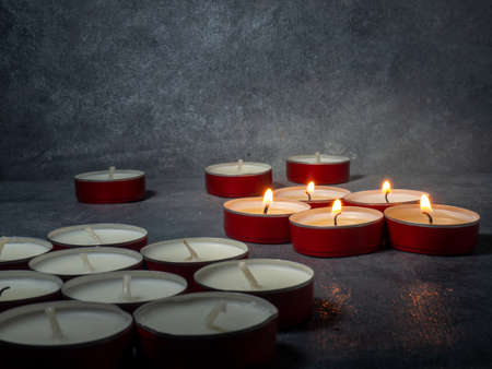 Short candles are burning against a dark background. Lots of small candles. Not all candles are lit. Extinguishedの写真素材