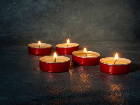 Small candles burn orange in the dark. Mysterious setting. Waiting for the holidayの写真素材