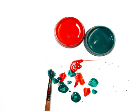 Jars of green and red acrylic paint on a white background and splattered paint on the table. Brushの写真素材