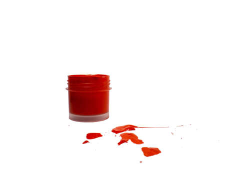 red acrylic in a jar on white background. drops of paint on the table.   colorの写真素材