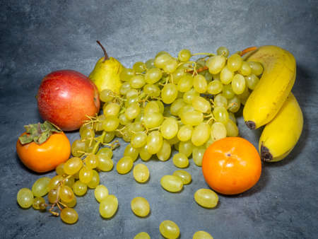 Still life of fruits. apple, persimmon, pear and grapes on a black background. Persimmon Chamomile. Apple Gala. Pear Lucas. Healthy eating. Vegetarianismの写真素材