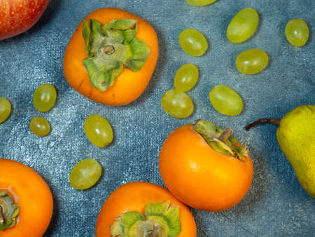 Apple, persimmon and pear on a black background. Persimmon Chamomile. Apple Gala. Pear Lucas. Still life of fruits. Fruit background. Healthy eating. Vegetarianismの写真素材