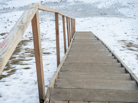 Wooden ladder in the snow. Descent to the water.の写真素材