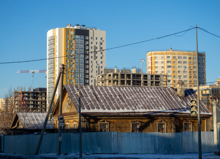 Urbanization. Old small houses against the background of large high-rise buildingsの写真素材