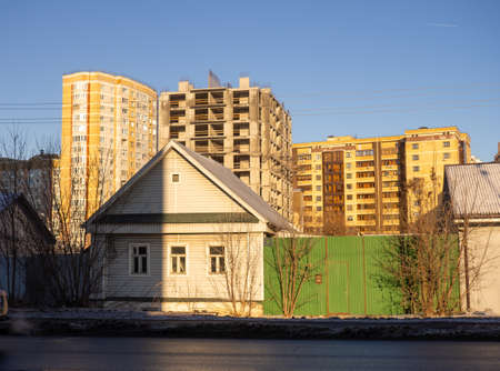 Urbanization. Old small houses against the background of large high-rise buildingsの写真素材