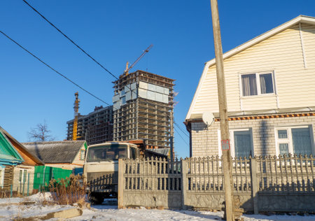 high-rise construction. Urbanization. Old small houses against the background of large high-rise buildingsの写真素材