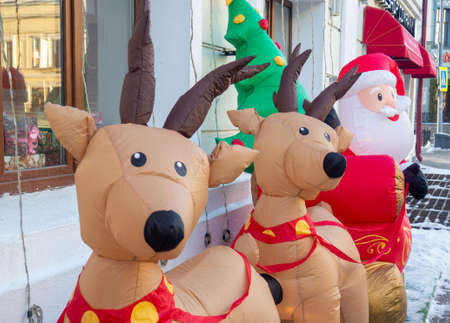 Inflatable Santa Claus and reindeer on the street. Christmas design. New Year's decoration on the street. The atmosphere of the holiday. Winter frosty streetの写真素材