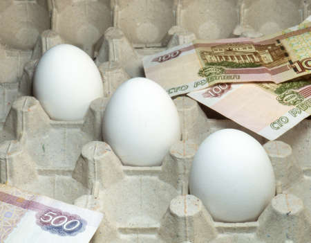 High cost. Imitation of products. Money with eggs. High price. Half-empty egg carton.  Eggs in an empty package. Leftover products. Leftover food. Few eggs.の写真素材