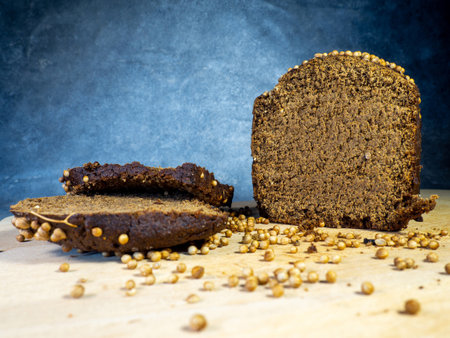Sliced ââbrown bread sprinkled with coriander. Borodino bread. Flour product. Bread with spices on kitchen board on black backgroundの写真素材