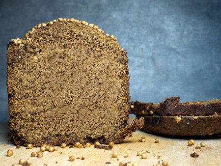 Sliced ââbrown bread sprinkled with coriander. Borodino bread. Flour product. Bread with spices on kitchen board on black backgroundの写真素材