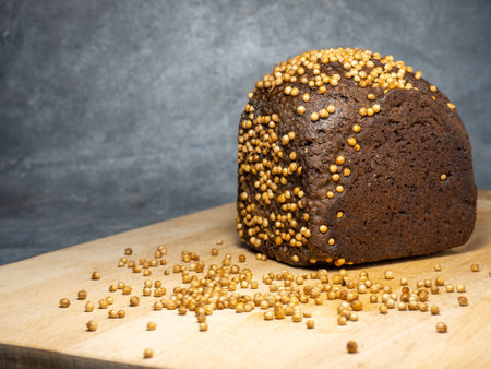 Black bread sprinkled with coriander. Borodino bread. Flour product. Bread with spices on kitchen board on black backgroundの写真素材