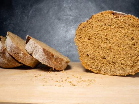 Sliced loaf of black bread on a kitchen board. Bread on a black background. Healthy food. Vegetarianismの写真素材