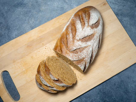 Sliced loaf of black bread on a kitchen board. Bread on a black background. Healthy food. Vegetarianismの写真素材