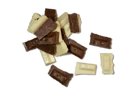 Slices of black and white chocolate on a white background. Various chocolates on the table. Background of sweet slicesの写真素材
