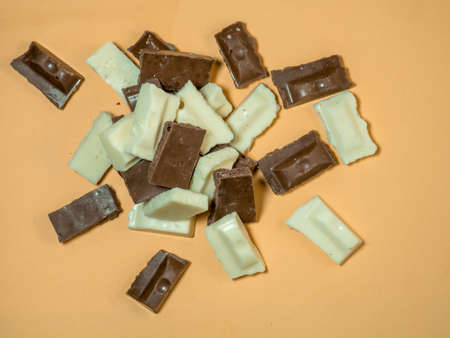 Slices of black and white chocolate on a beige background. Slices from a bar of chocolate. Sweet slices backgroundの写真素材