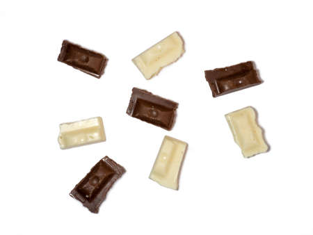 Slices of black and white chocolate on a white background. Various chocolates on the table. Background of sweet slicesの写真素材