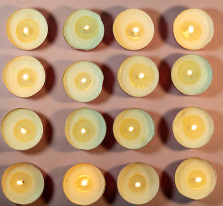 Burning round candles on a pink background. Fire pattern. Candle flame. candle shadowsの写真素材
